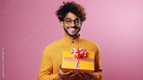 Young indian man smiling while holding gift box photo