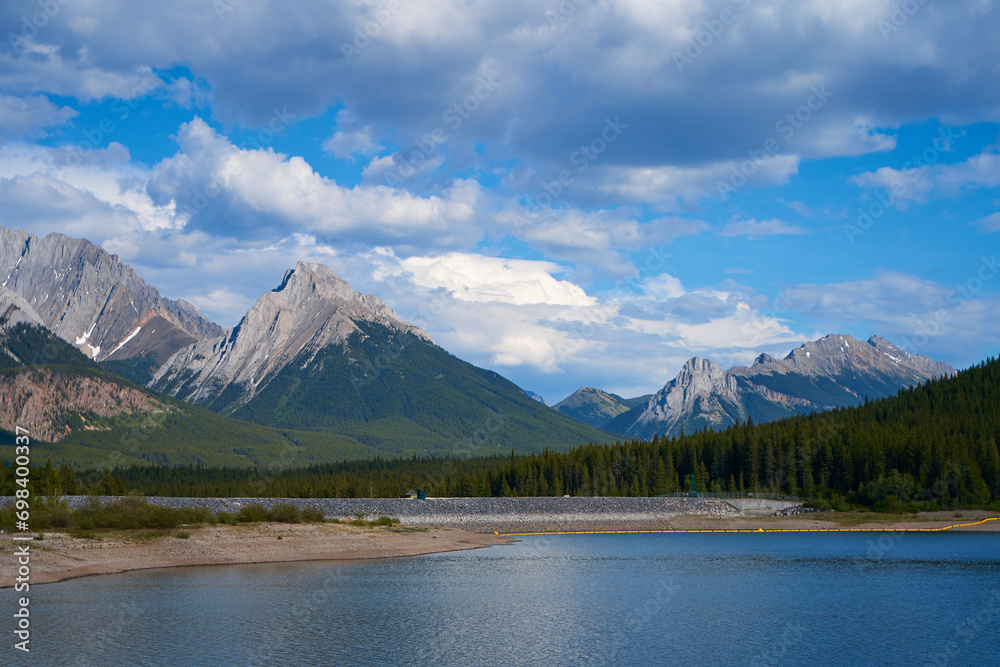 An incredible view of a natural mountain lake on a sunny summer day against the backdrop of the rocky mountains of Alberta in Canada.