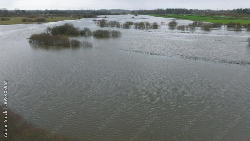 Aerial establishing view of high water in springtime, Alande river (Latvia) flood, brown and muddy water, agricultural fields under the water, overcast day, wide drone shot moving forward low Aerial establishing view of high water in springtime, Alande river (Latvia) flood, brown and muddy water, agricultural fields under the water, overcast day, wide drone shot moving forward low