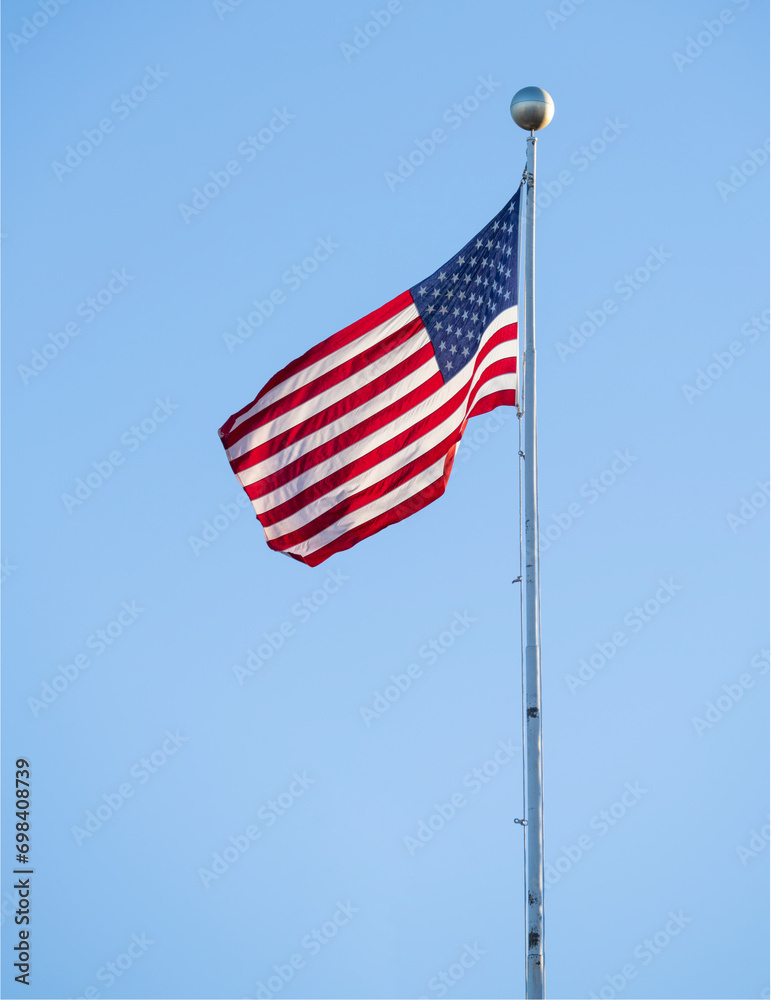 waving USA flag on pole against blue sky waving USA flag on pole against blue sky