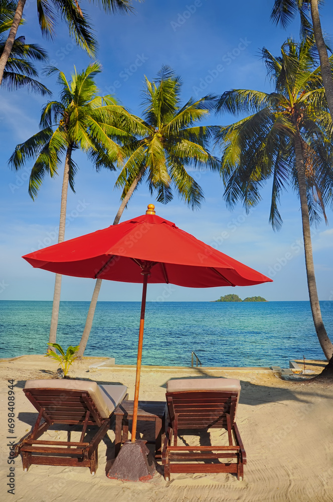 Sun chair under red umbrella on a tropical sandy beach