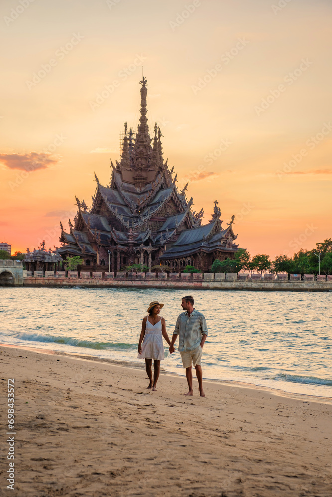 A diverse multiethnic couple of men and women visit The Sanctuary of Truth wooden temple in Pattaya Thailand. a wooden temple construction located at the cape of Naklua Pattaya City Chonburi A diverse multiethnic couple of men and women visit The Sanctuary of Truth wooden temple in Pattaya Thailand. a wooden temple construction located at the cape of Naklua Pattaya City Chonburi