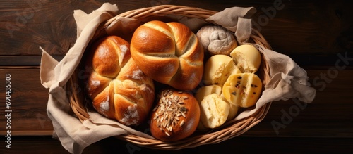 Assorted soft and stretchy sweet bread in dish on table with butter, top-down view photo