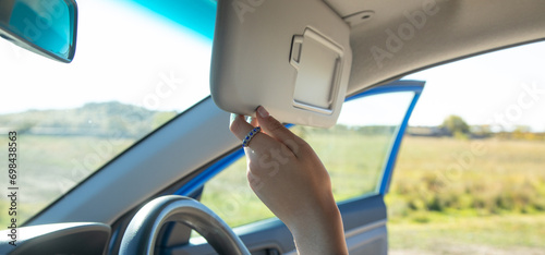 Female hand adjusting sun visor in a car.