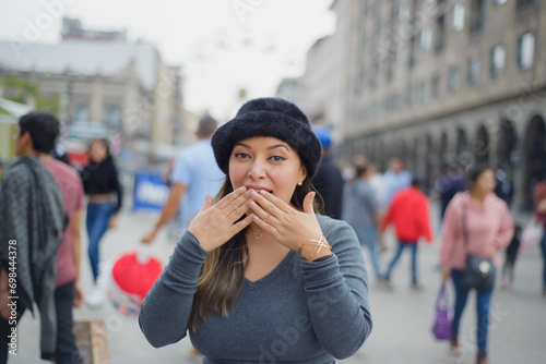 Latin woman with surprised attitude in the middle of the street. People in background.