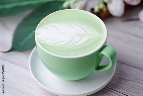 Close-up of a green coffee cup with a feather latte art design.