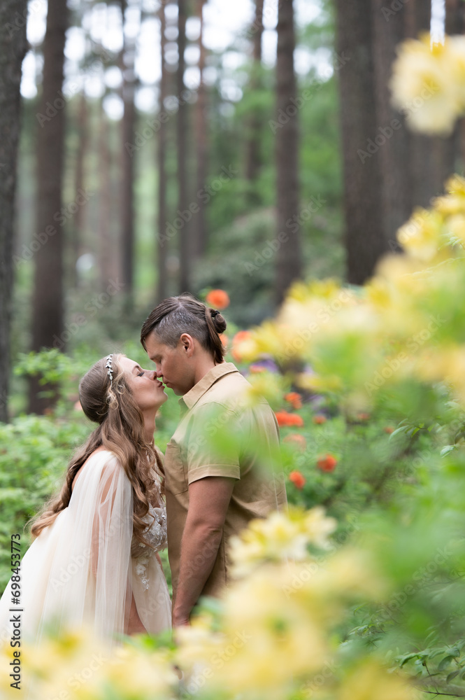 Hapy pregnant couple kissing in blossom garden. Future parents in blooming rhododendron park. Hapy pregnant couple kissing in blossom garden. Future parents in blooming rhododendron park.