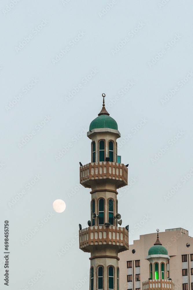 view of mosque huge tall minarets in green muslim symbol and several domes in the city sky with half moon risen 