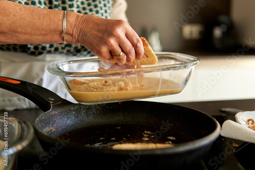 Primer plano de las manos de una abuela friendo torrijas españolas de Semana Santa con la receta tradicional en una vitrocerámica actual. photo