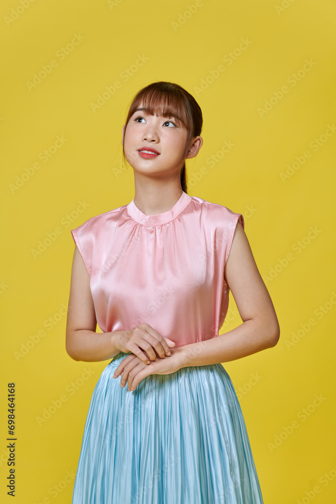 Portrait of a cheerful young girl in dress looking at camera isolated over yellow background Portrait of a cheerful young girl in dress looking at camera isolated over yellow background