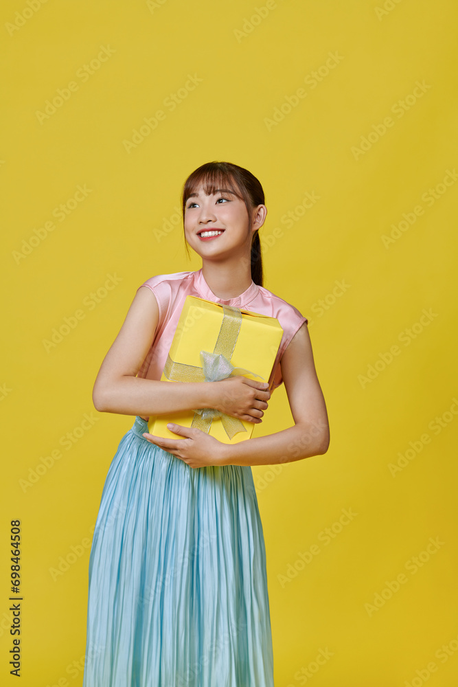 Full length portrait of a happy woman holding gifts isolated on a yellow background Full length portrait of a happy woman holding gifts isolated on a yellow background