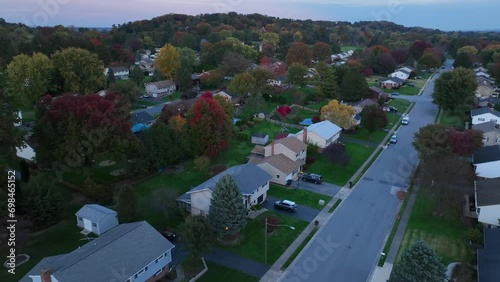 Autumn trees and houses in American neighborhood at dusk. Aerial shot above homes at after sunset. photo