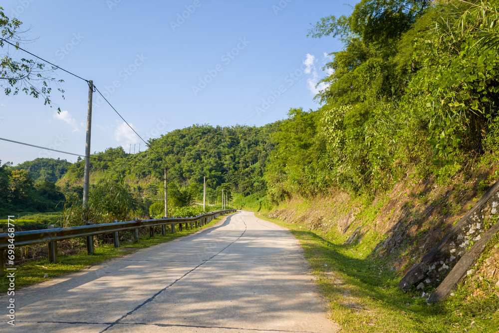 A road in the middle of the green mountains in the countryside, Asia, Vietnam, Tonkin, Dien Bien Phu, in summer, on a sunny day.