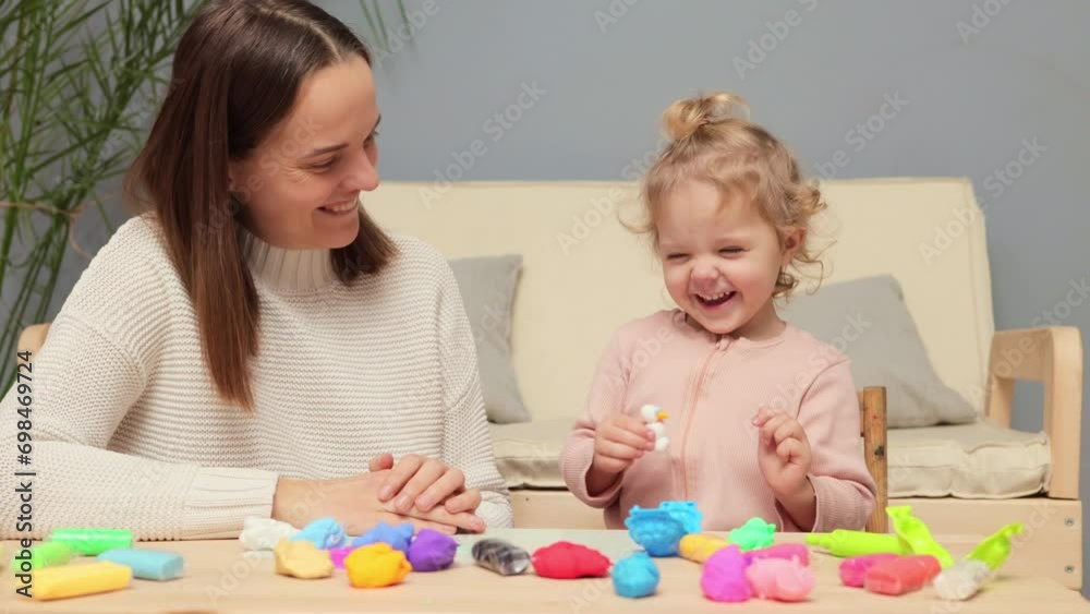 Playdough in kindergarten. Educational handcraft with dough. Mother teaching creativity. Cheerful adorable Caucasian kid girl and mother playing colorful clay plasticine at home Playdough in kindergarten. Educational handcraft with dough. Mother teaching creativity. Cheerful adorable Caucasian kid girl and mother playing colorful clay plasticine at home