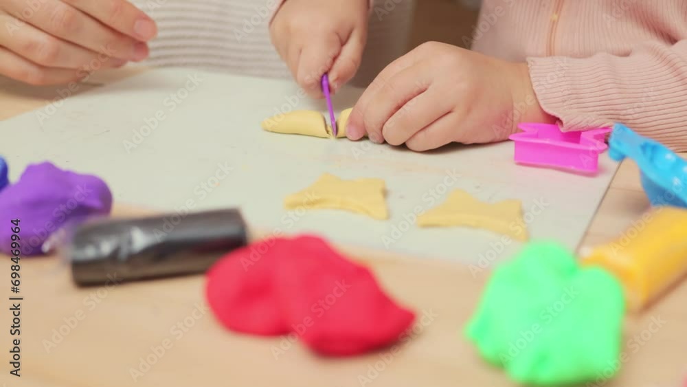 Family creativity at home. Soft and colorful fun. Preschool handcraft session. Unrecognizable kid girl and mother playing colorful clay plasticine together in home interior Family creativity at home. Soft and colorful fun. Preschool handcraft session. Unrecognizable kid girl and mother playing colorful clay plasticine together in home interior