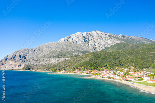 The town on the rocky coast in the middle of green countryside , Europe, Greece, Aetolia Acarnania, Kato Vasiliki towards Patras, by the Ionian Sea, in summer on a sunny day.