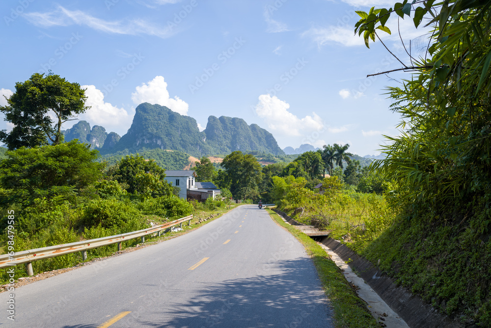 An asphalt road in the middle of the countryside and mountains, in Asia, in Vietnam, in Tonkin, towards Hanoi, in Mai Chau, in summer, on a sunny day.