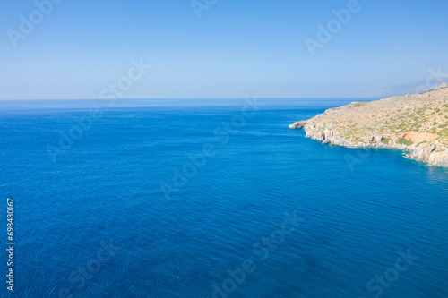 The arid rocky coast and its green countryside along small beaches, in Europe, Greece, Crete, towards Preveli, At the edge of the Mediterranean Sea, in summer, on a sunny day.