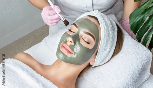Woman receiving a Facial Clay Mask in Wellness Resort or Spa - Relaxation and Skin Care done by Beautician photo