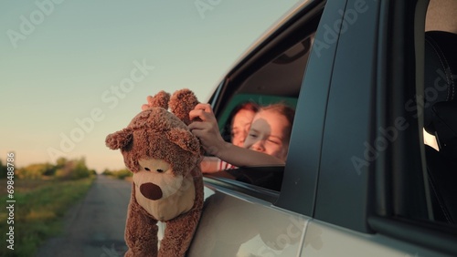 little girl with toy bear. happy face child daughter from window with teddy bear. happy family. mother daughter traveling car. happy mother child back seat car going trip. face childish smile. photo