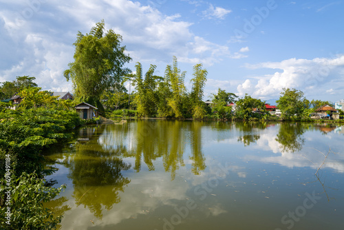Trees by a lake near a traditional village , Asia, Vietnam, Tonkin, Dien Bien Phu, in summer on a sunny day.