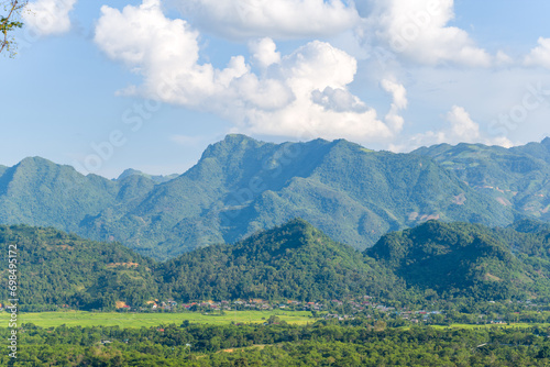 A city in the valley among green rice fields and green mountains, Asia, Vietnam, Tonkin, between Son La and Dien Bien Phu, in summer on a sunny day. © Florent