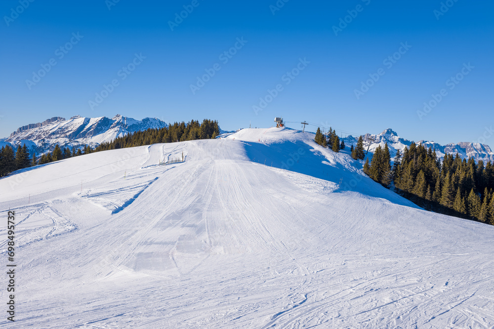 A Megeve ski slope in the middle of the mountains of the Mont Blanc massif in Europe, France, Rhone Alpes, Savoie, Alps, in winter, on a sunny day.