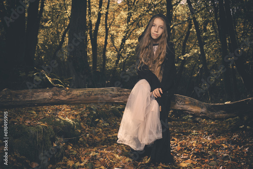 Young girl in halloween style posing in autumn forest photo