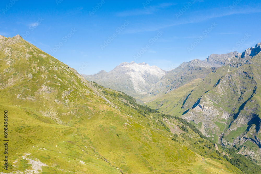 The Mountains around Gavarnie Gedre in the arid green countryside , Europe, France, Occitanie, Hautes-Pyrenees, in summer on a sunny day.