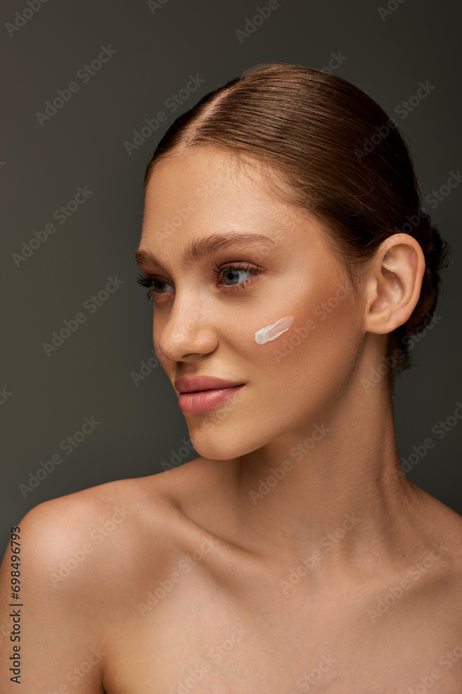 beautiful young woman with cream on face and bare shoulders posing on grey background, look away beautiful young woman with cream on face and bare shoulders posing on grey background, look away