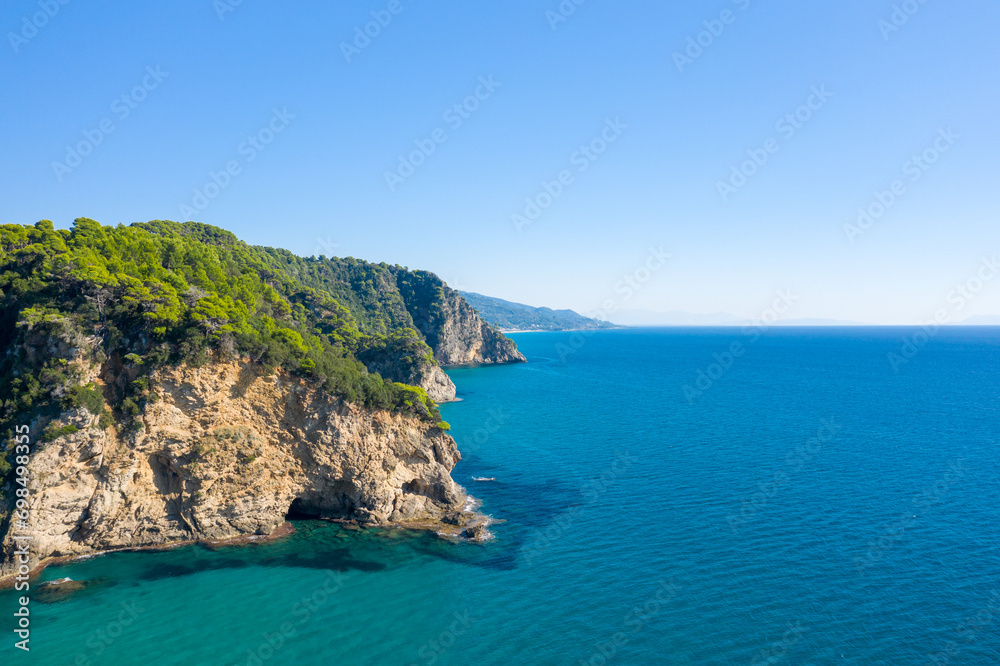 The rocky and green coast, in Europe, in Greece, in Epirus, towards Igoumenitsa, by the Ionian Sea, in summer, on a sunny day.