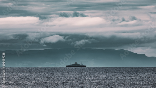 Dramatic clouds before the storm. Ship against the background of mountains in the Trondheim fjord.