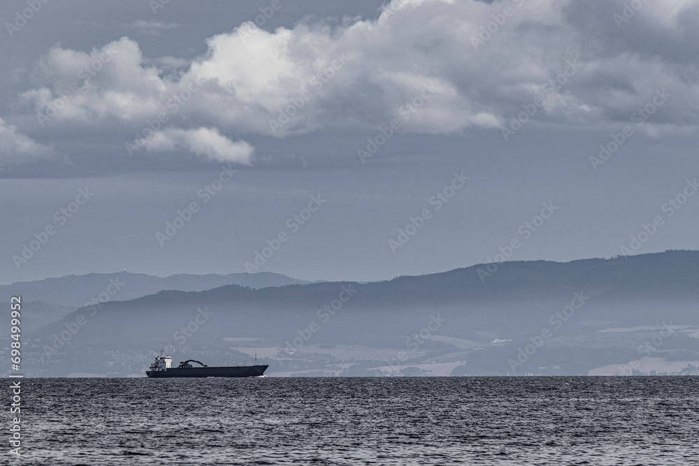 Ship against the background of mountains in the Trondheim fjord. Dramatic clouds before the storm. Ship against the background of mountains in the Trondheim fjord. Dramatic clouds before the storm.