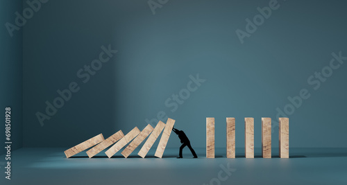 Silhouette of a man in panic against collapsing wooden dominos. Business crisis and failure concept in wide view. photo