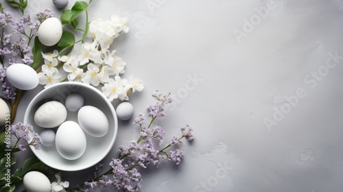  a white bowl filled with white eggs next to a bunch of white flowers on a gray and white tablecloth.