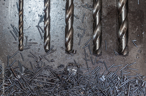 Drill bits for drilling steel lie on steel shavings close-up.