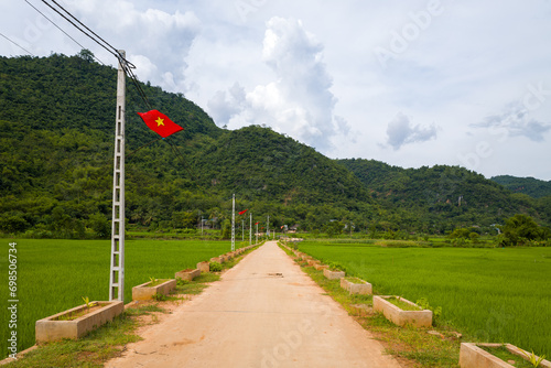 A path in the middle of the green rice fields in the mountains, in Asia, in Vietnam, in Tonkin, towards Hanoi, in Mai Chau, in summer, on a sunny day.
