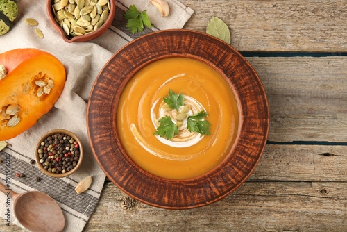 Delicious pumpkin soup served on wooden table, flat lay