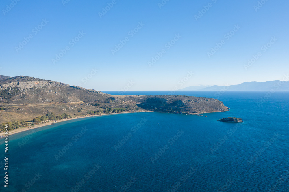 The arid rocky coast and its green countryside along small beaches, in Europe, Greece, Peloponnese, Argolis, Nafplio, Myrto seashore, in summer, on a sunny day. The arid rocky coast and its green countryside along small beaches, in Europe, Greece, Peloponnese, Argolis, Nafplio, Myrto seashore, in summer, on a sunny day.