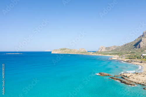 The sandy beach at the foot of the rocky cliffs in the arid countryside , in Europe, Greece, Crete, towards Kissamos, towards Chania, By the Mediterranean Sea, in summer, on a sunny day. © Florent