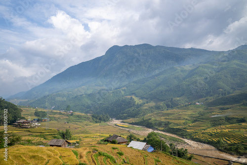 The yellow and green rice terraces above the valley in the green mountains, Asia, Vietnam, Tonkin, Sapa, towards Lao Cai, in summer, on a cloudy day. photo