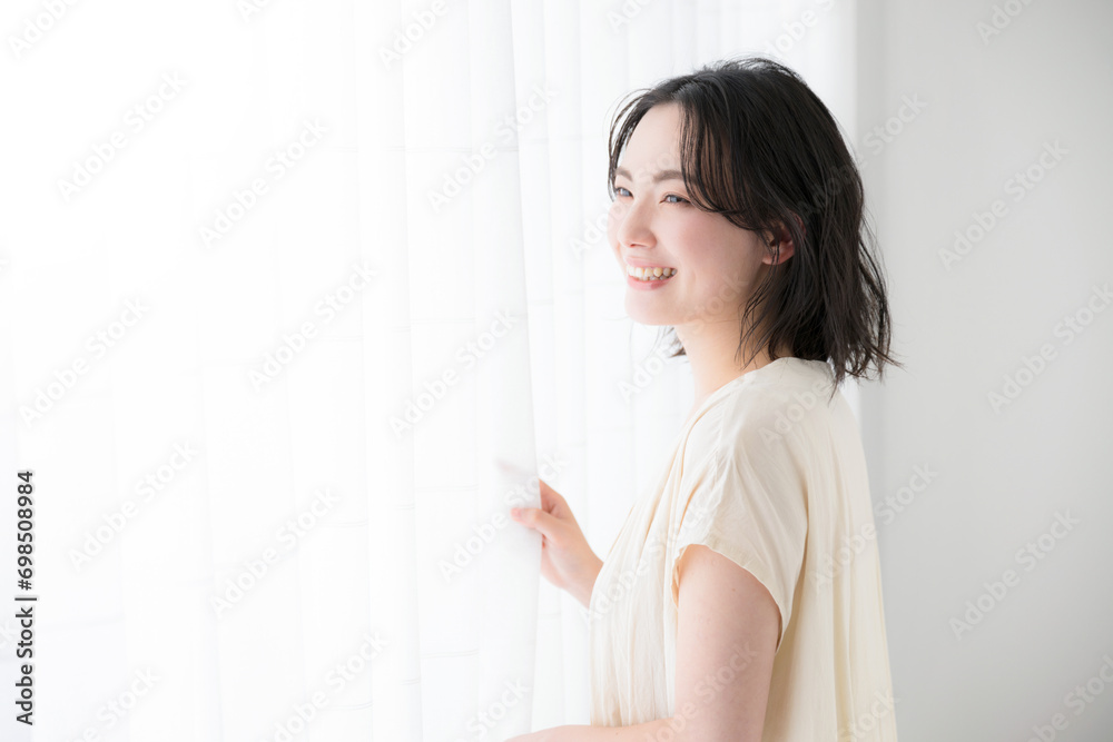 Young woman standing by the window, smiling profile Young woman standing by the window, smiling profile