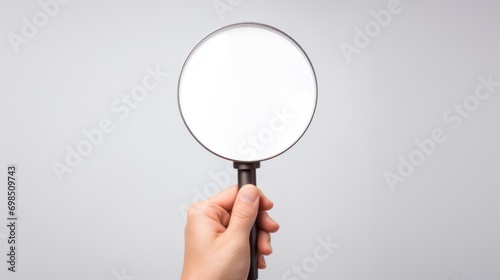  a person's hand holding a magnifying glass with a white blank space in the middle of it.