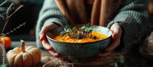 Young woman consuming pumpkin soup in kitchen close-up.