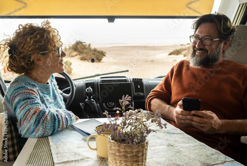 Couple enjoys the weekend aboard their camper. Happy man together with his wife spending pleasant moments. Concept of freedom and free time #698520150