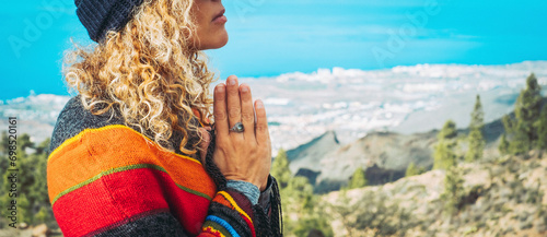 Close-up of calm young Caucasian woman holding hands on heart chest and feeling grateful and grateful. Happy female shows gratitude, love and care, prays or displays. Religion, faith concept. photo