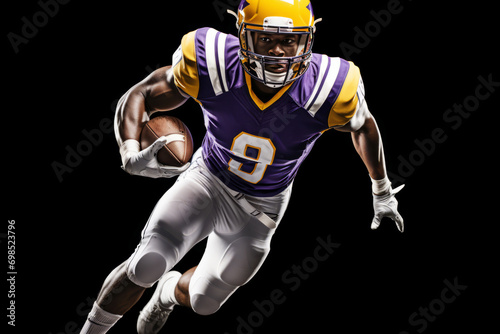 Portrait of American football player running with the ball. Muscular athlete in a purple and yellow uniform with an ovoid ball in a dynamic pose. Isolated on black background.