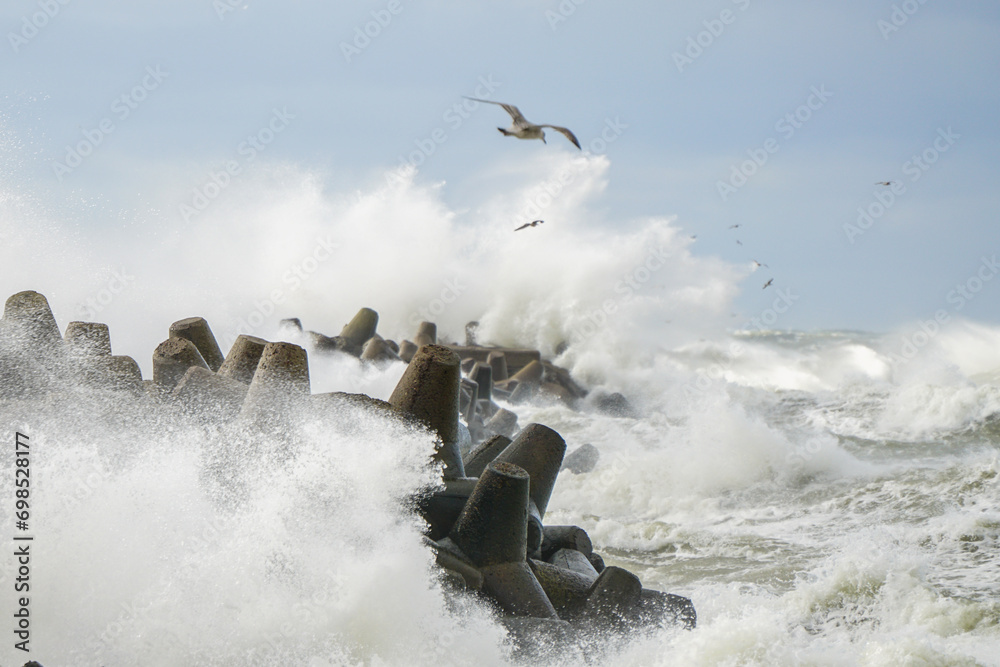High white splashes from waves crashing against the harbor's concrete breakwater in a storm - obrazy, fototapety, plakaty 