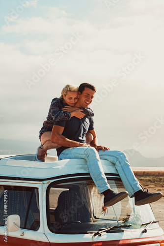 Young couple of traveler enjoy van life vehicle travel adventure together hugging and loving sitting on the roof of the classic camper. Freedom and campingcar road trip for happy free people