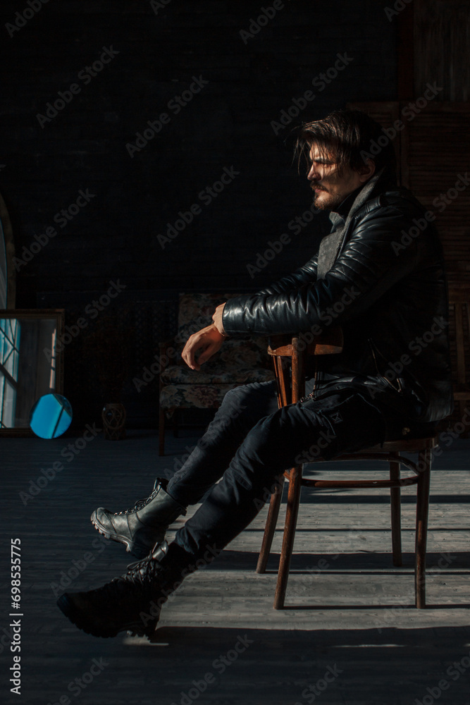 handsome man in black clothes sitting on a chair - obrazy, fototapety, plakaty 